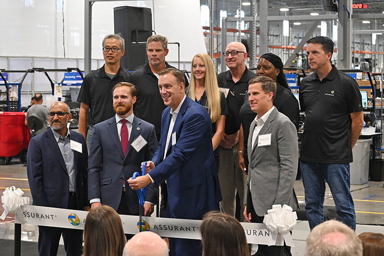 Assurant Inc. President and CEO Keith Demmings, holding ceremonial scissors, is joined by Stuart McWhorter, commissioner for the Tennessee Department of Economic and Community Development, left of Demmings, along with other Assurant executives and team members Oct. 10 as they prepare to cut the ribbon to officially open the device care company’s Mt. Juliet, Tenn., facility. The new location is double the size of the previous location in La Vergne, Tenn., and will be a key hub for Assurant’s Device Lifecyle Solutions business. (MTSU photo by Jimmy Hart)