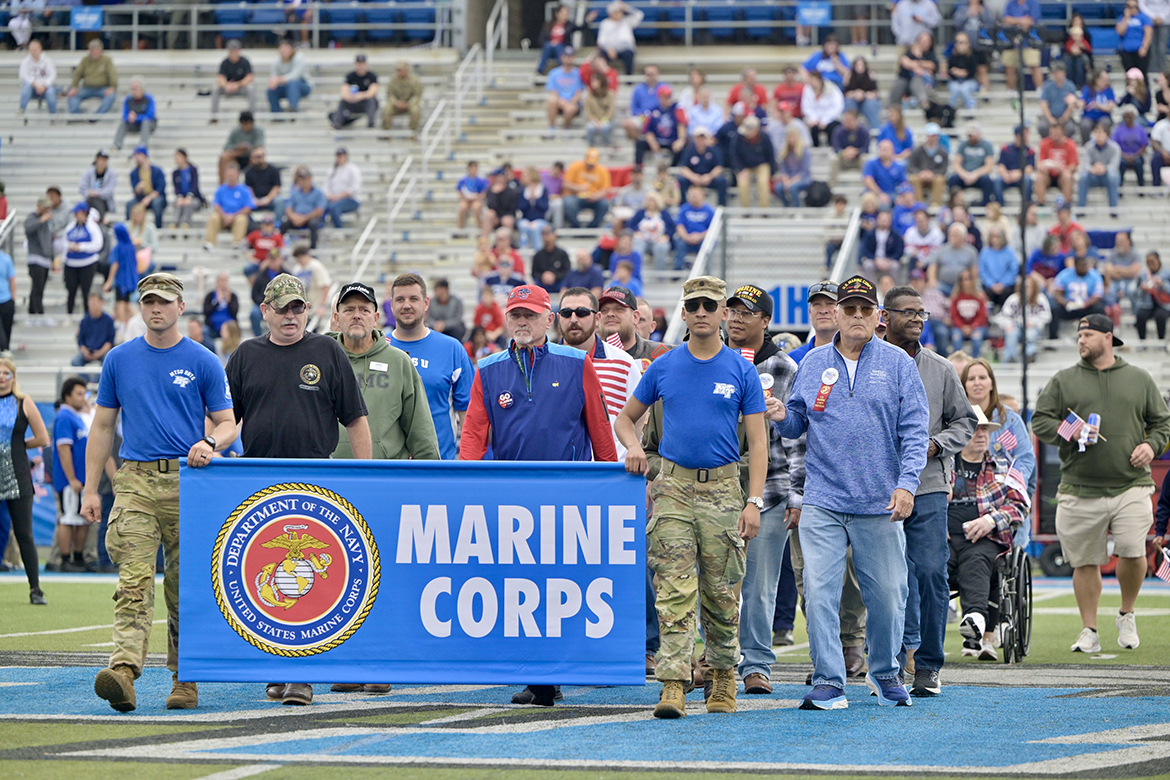 Led by Middle Tennessee State University ROTC cadets Matthew Chappell, left, and George Jouny carrying the U.S. Marine Corps banner, a group of Marine veterans go across Horace Jones Field in Floyd Stadium while the Band of Blue performs their theme song, “The Marines Hymn,” Saturday, Nov. 9, as part of 42nd annual Salute to Veterans and Armed Forces game activities on the campus in Murfreesboro, Tenn. A picnic and other events led up to the Conference USA game, with the Liberty University Flames defeating the MTSU Blue Raiders 37-17. (MTSU photo by Andy Heidt)