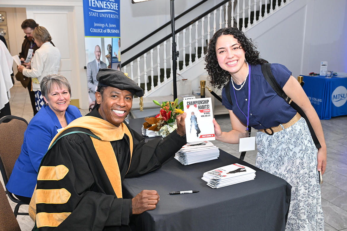 Internationally known educator, author and keynote speaker Adolph “Doc” Brown, left, presents an attendee with a signed copy of his book, “Championship Habits,” following Middle Tennessee State University’s 2024 Leadership Summit hosted Oct. 25 by the Jones College of Business at the Stones River Country Club in Murfreesboro, Tenn. Seated behind Brown is Jones College Dean Joyce Heames. (MTSU photo by James Cessna)