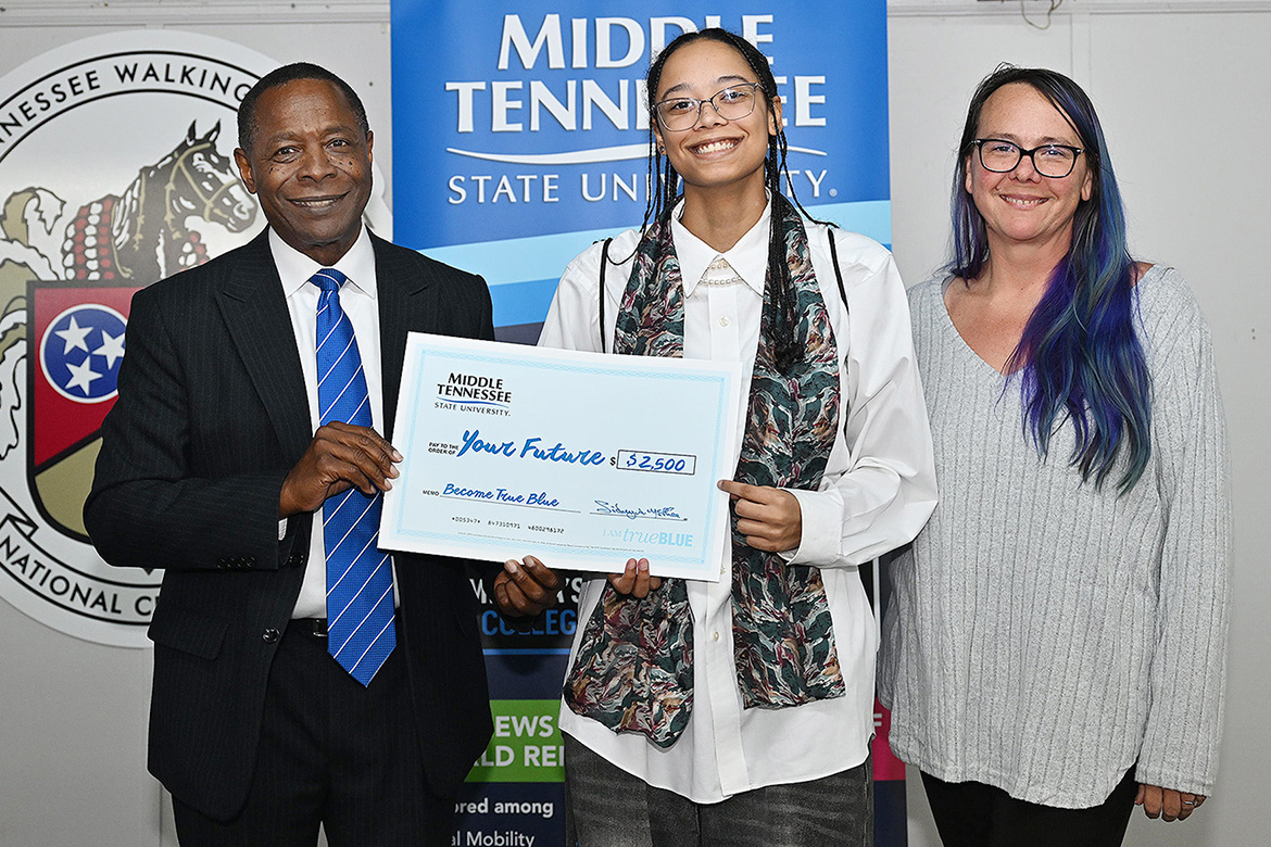 Sidney A. McPhee, left, president of Middle Tennessee State University in Murfreesboro, Tenn., gives a $2,500 scholarship to Coffee County High School senior Kayden Nelson, who is joined by her mother, Melissa Nelson, right, at the MTSU True Blue Tour student recruitment event held Monday, Nov. 18, at the Blue Ribbon Circle in Shelbyville. (MTSU photo by James Cessna)