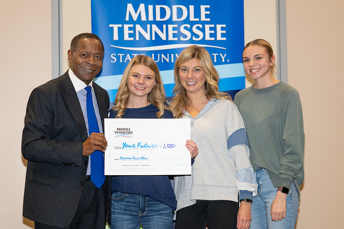 Sidney A. McPhee, left, president of Middle Tennessee State University in Murfreesboro, Tenn., gives a $2,500 scholarship to Franklin County High School senior Molli Hyde, who is joined by her mother, Brandi Curtis, and cousin Anna Grace Elliott, far right, at the MTSU True Blue Tour student recruitment event held Thursday, Nov. 21, at the Farm Bureau Expo Center in Lebanon. (MTSU photo by Cat Curtis Murphy)