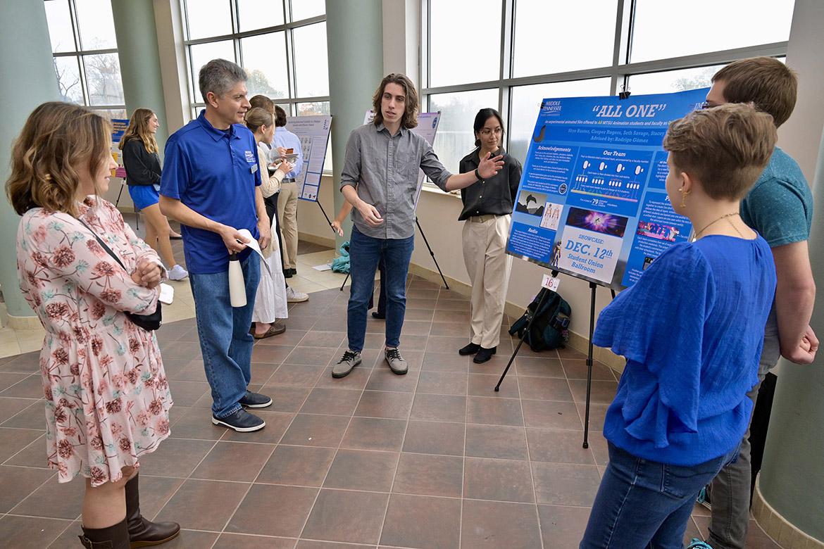 Middle Tennessee State University animation students stand beside their faculty mentor, Rodrigo Gomez, associate professor in the Department of Media Arts, as they discuss their upcoming film premiere to an attendee at the seventh annual Undergraduate Research Center Fall Research and Creative Activity Open House held Thursday, Nov. 7, in the Miller Education Center on campus in Murfreesboro, Tenn. (MTSU photo by Andy Heidt)