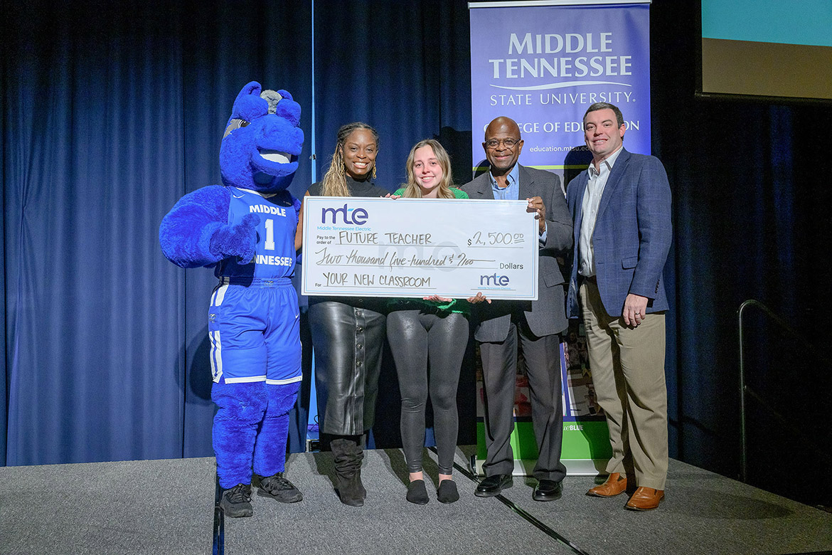 Middle Tennessee State University student Natalie Burridge, third from left, holds the $2,500 Spark Award check she was presented Dec. 12 in the James Union Building on campus in Murfreesboro, Tenn. Middle Tennessee Electric awarded the College of Education $40,000 to outfit future teacher classrooms each semester for the next four years through the awards. Pictured, from left, are Lightning, the university’s mascot; Neporcha Cone, education dean; Robert White, MTE vice president of communications and member services; and Jay Sanders, MTE community relations coordinator. (MTSU photo by J. Intintoli)