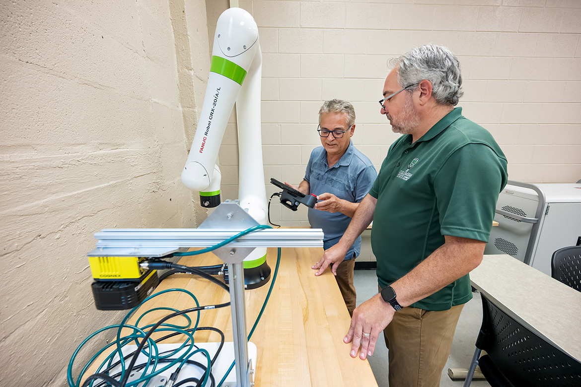 Columbia State Community College Business and Technology Dean Mehran Mostajir, left, shows Development Officer Patrick McElhiney how to use a FANUC robotic system arm that is available to Middle Tennessee State University students and potential Columbia State transfer students in a classroom laboratory on the MTSU campus in Murfreesboro, Tenn., earlier this year. Columbia State and MTSU received a nearly $350,000 National Science Foundation grant to assist the Midstate region in certifying future technicians and engineers in robotics and automation systems for the next three years. (MTSU photo by Andy Heidt)