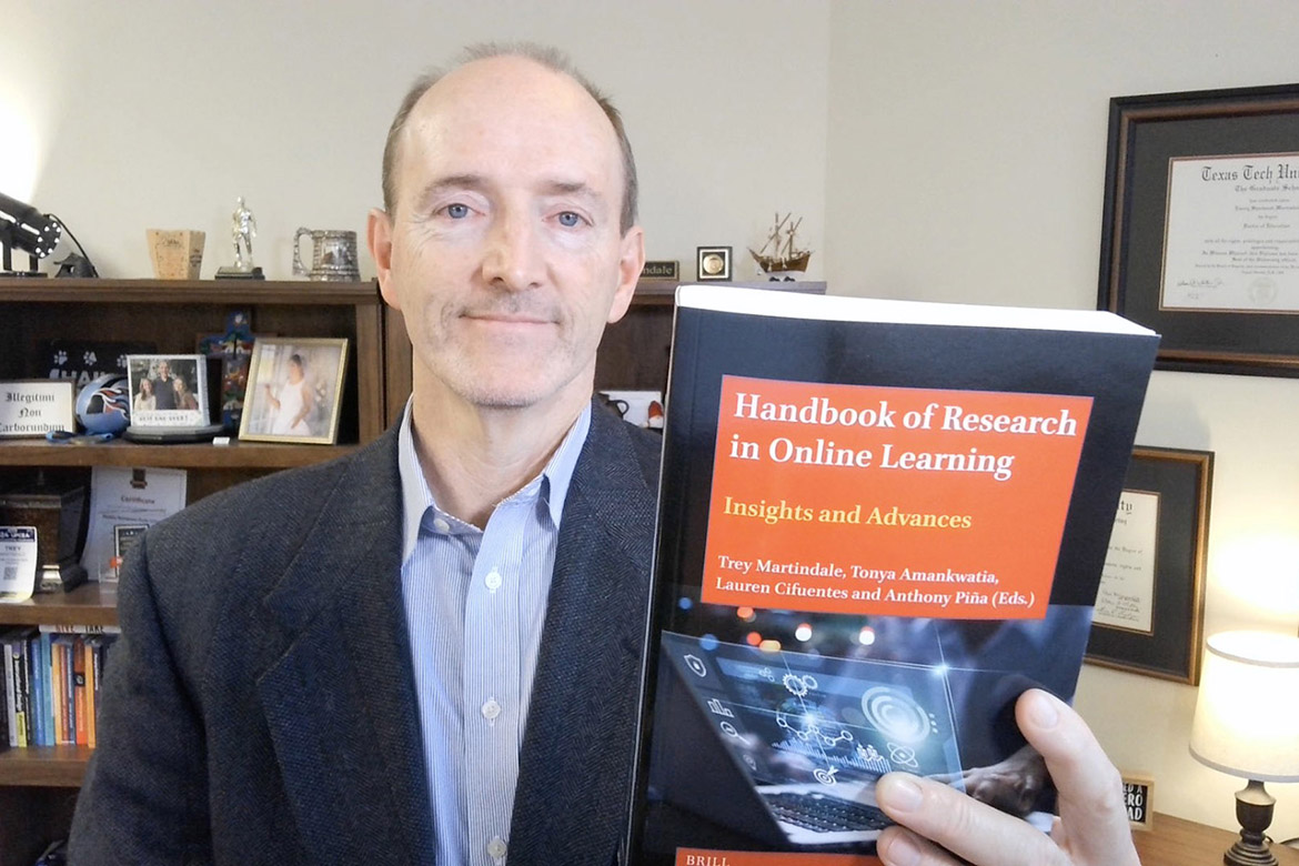 Trey Martindale, Middle Tennessee State University’s associate vice provost for online learning, holds up his recently published book, “Handbook of Research in Online Learning,” where he was the lead editor and co-writer in Murfreesboro, Tenn. Martindale and his team in MTSU Online saw record enrollment for online courses this fall. (Photo submitted)