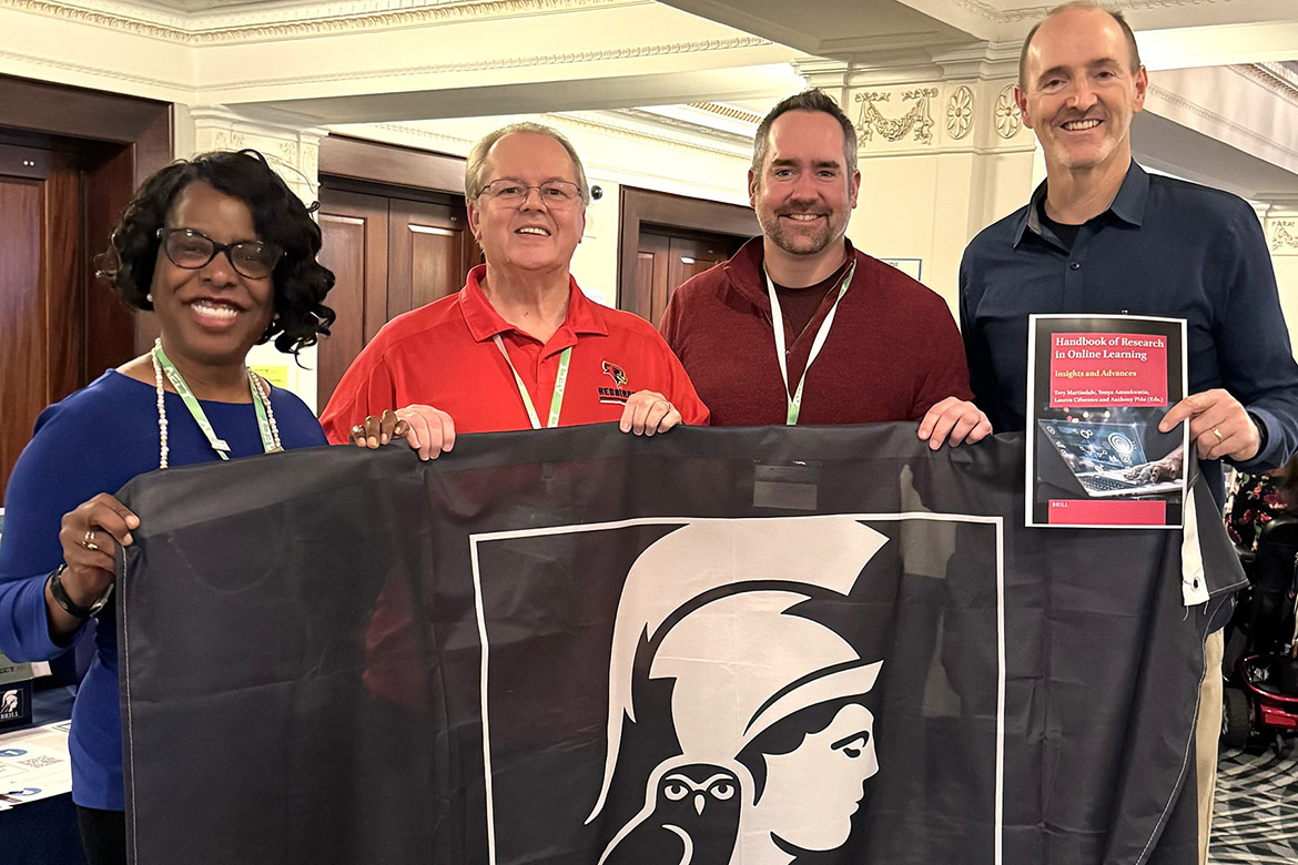 Middle Tennessee State University’s Trey Martindale, far right, associate vice provost for online learning, stands with some of the collaborators for his recently published book, “Handbook of Research in Online Learning.” Pictured with him, from left, are co-editors Tonya Amankwatia from North Carolina Agricultural and Technical State University and Tony Pina from Illinois State University, and John Bennett from Brill Publishers, who was the publishing company for their book. The four hold the Brill Publishers flag and Martindale holds a photo of the book’s cover. (Photo submitted)