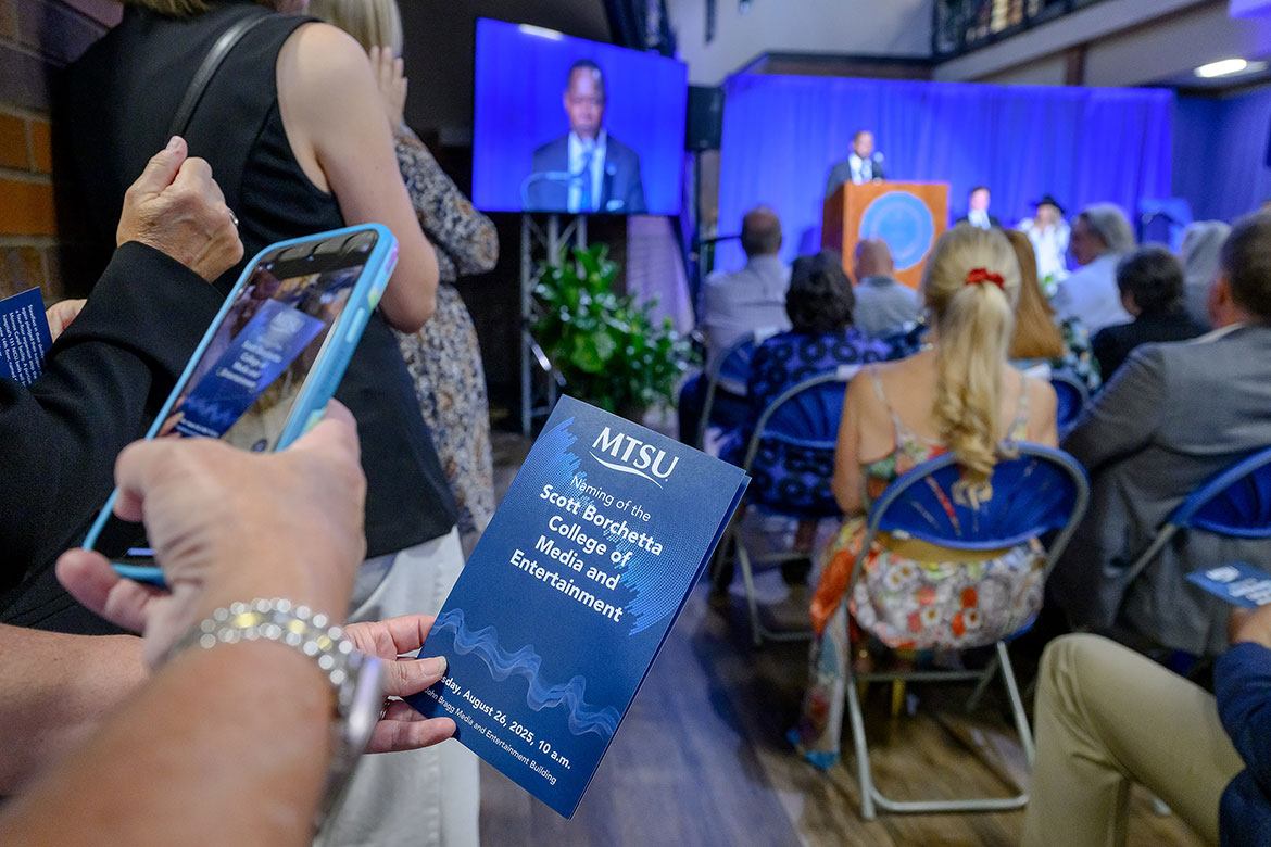 As Middle Tennessee State University President Sidney A. McPhee gives remarks at the podium, an attendee grabs a photo of the commemorative program at the special ceremony to announce the renaming of MTSU’s media college to the Scott Borchetta College of Media and Entertainment in honor of the Big Machine Label Group founder, chairman and CEO. The announcement was held before a capacity crowd in the atrium of the John Bragg Building on campus in Murfreesboro, Tenn. (MTSU photo by J. Intintoli)