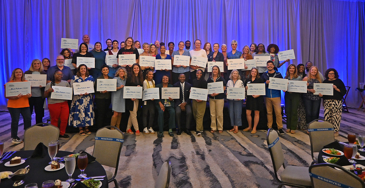 A large group of high school and community college counselors display the scholarship checks they received from Middle Tennessee State University in Murfreesboro, Tenn., during the university’s True Blue Tour counselors luncheon Sept. 25 at The Chattanoogan Hotel in Chattanooga, Tenn. MTSU President Sidney A. McPhee, seated center, presented checks to the almost 90 counselors who attended to distribute to students at their schools. (MTSU photo by Jimmy Hart)