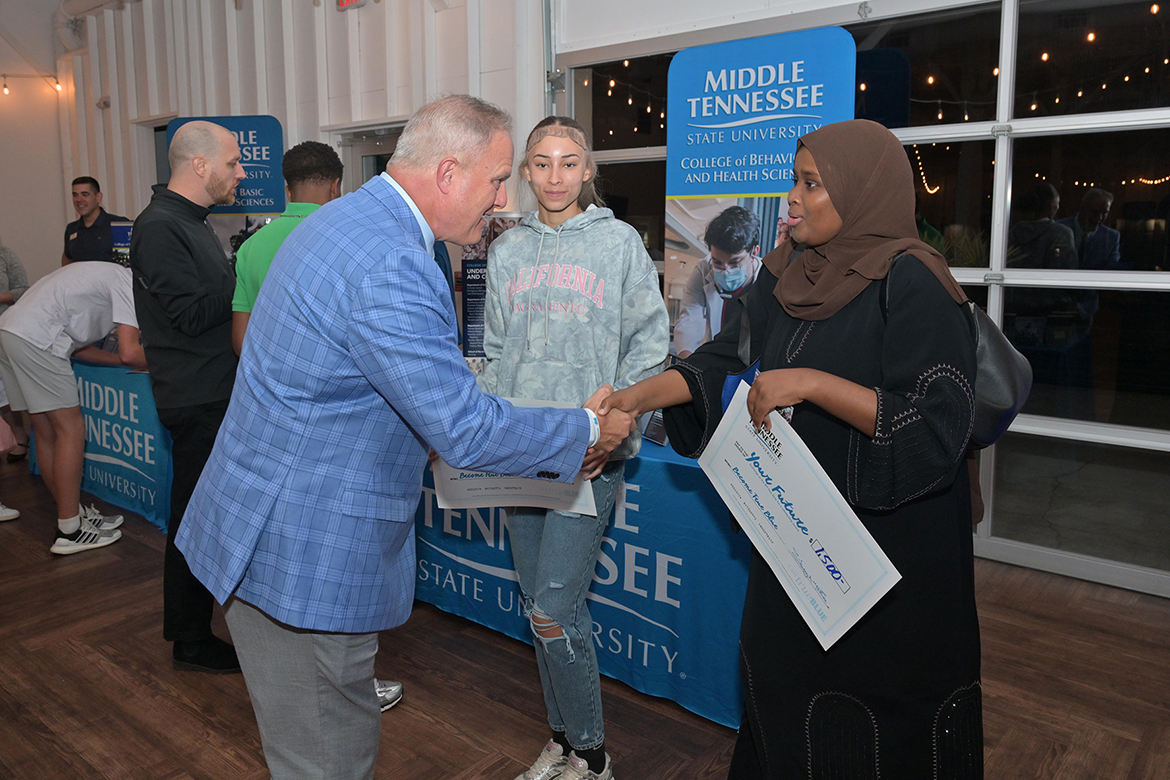 Peter Grandjean, dean of the College of Behavioral and Health Sciences at Middle Tennessee State University in Murfreesboro, Tenn., talks with Maryan Mohamud, right, during the recent True Blue Tour student recruitment stop at 14TENN event center in Nashville on Monday, Sept. 29. Mohamud and Carlesia Burns, center, hold the ceremonial scholarship checks they were awarded earlier in the evening. (MTSU photo by James Cessna)