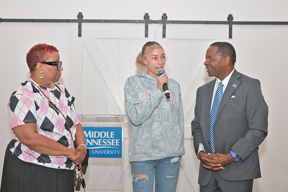 Middle Tennessee State University President Sidney A. McPhee, right, listens as Battleground Academy senior Carlesia Burns, center, shares a bit about herself with the crowd gathered at the recent True Blue Tour student recruitment initiative held at 14TENN event center in Nashville on Monday, Sept. 29. Looking on at left is her mother, Teresa Burns. (MTSU photo by James Cessna)