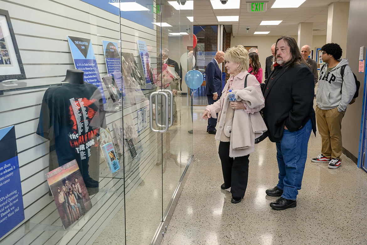 Hazel Daniels, foreground left, and Charlie Daniels Jr. admire the glass case tribute of memorabilia paid to the late country music legend Charlie Daniels by the Middle Tennessee State University Charlie and Hazel Daniels Veterans and Military Family Center staff in the Keathley University Center Theater on campus in Murfreesboro, Tenn., during the center’s 10th anniversary celebration on Monday, Nov. 3. (MTSU photo by J. Intintoli)