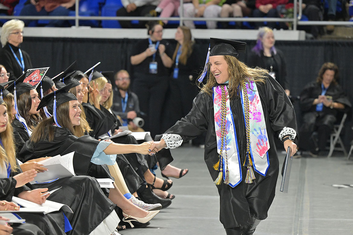 A graduate shakes the hand of a fellow student after receiving her diploma during the fall 2025 morning commencement ceremony held Saturday, Dec. 13, inside Murphy Center on the campus of Middle Tennessee State University in Murfreesboro, Tenn. (MTSU photo by James Cessna)