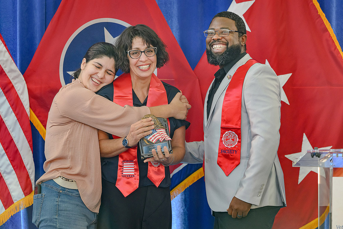 Chris Rochelle, assistant director of the Charlie and Hazel Daniels Veterans and Military Family Center at Middle Tennessee State University in Murfreesboro, Tenn., presents political science major Angela Ipock, center, with the Journey Award as Erin Kelsey embraces her mother at the 32nd Graduating Veterans Stole Ceremony held Thursday, Dec. 11, 2025, at Miller Education Center. (MTSU photo by Andy Heidt)