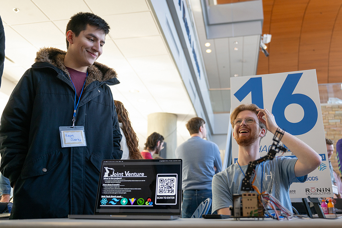 Middle Tennessee State University computer science major Kevin Juarez from Nashville, Tenn., left, listens to his teammate Ryan Vander Stelt, a computer science major from Lipscomb University in Nashville, Tenn., explain their project at the 11th annual MTSU Computer Science Department HackMT competition held on campus in Murfreesboro, Tenn. The 36-hour competition showcased app, computer and web projects. (MTSU photo by Cat Curtis Murphy)