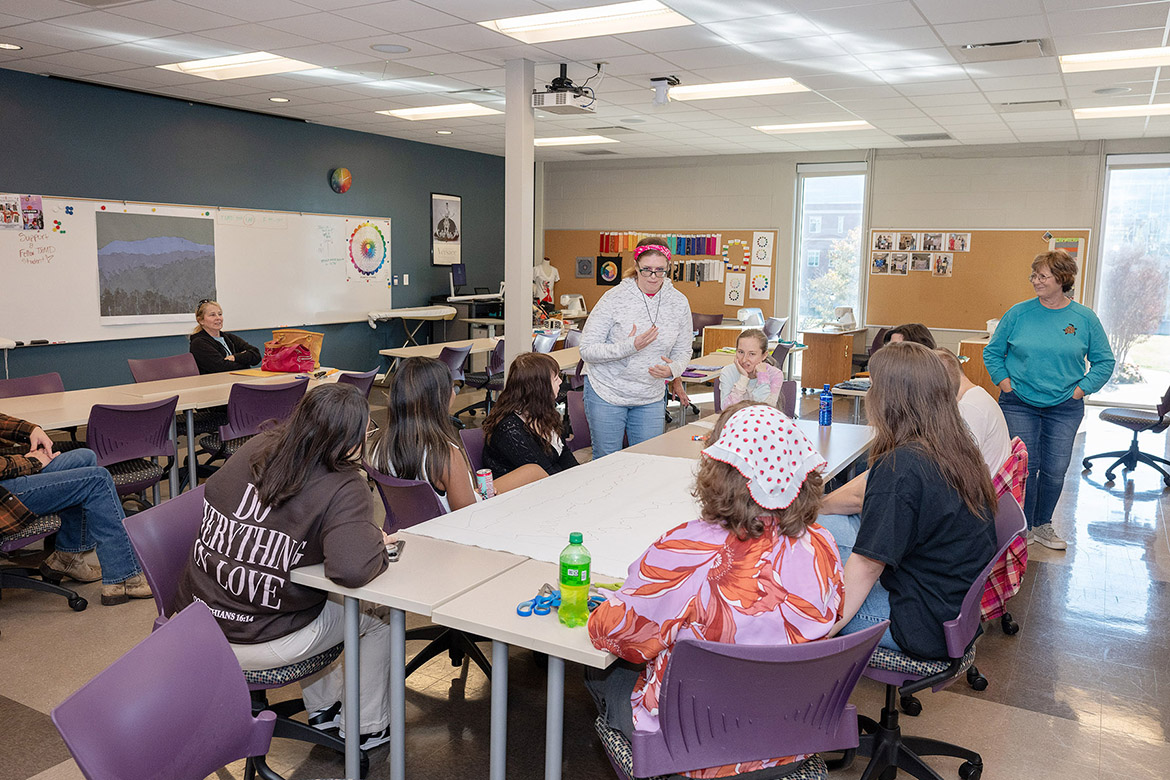 Borderless Arts Tennessee members Erica McMurray, standing at center, and Jennifer Scallorn, seated next to hear at right, along with Robin Summers, standing at right, talk with students in the Learning Resource Center sewing lab at Middle Tennessee State University in Murfreesboro, Tenn., before an art project that will be on display as part of the state’s celebration of the United States’ 250th anniversary. (MTSU photo by James Cessna)