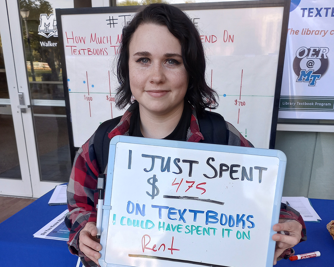 Marissa Farabee, a history major at Middle Tennessee State University in Murfreesboro, Tenn., holds a sign that notes her textbook costs during an Open Educational Resources, or OER, tabling event on campus in October 2023. Over the past five years, MTSU students have saved more than $3 million in textbook costs through OER. (Submitted photo)