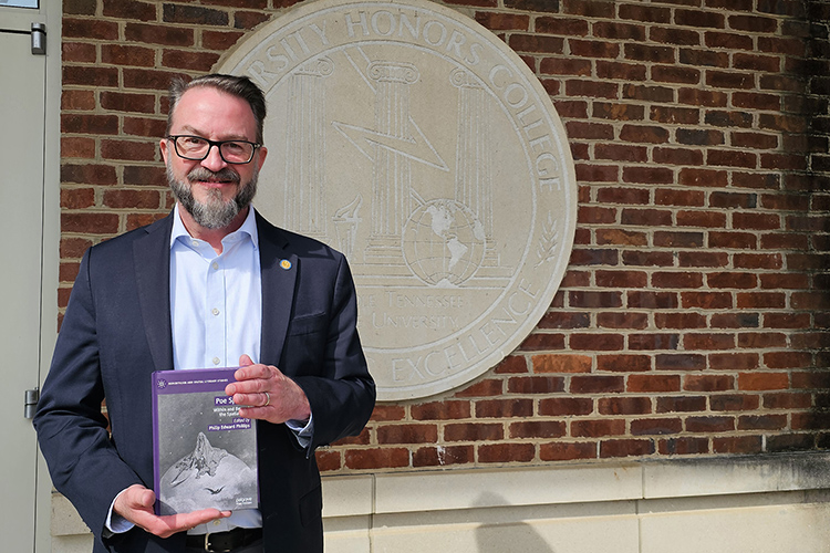 Shown here outside the Paul W. Martin Sr. Honors Building at Middle Tennessee State University in Murfreesboro, Tenn., Philip Phillips, Honors College associate dean and English professor, holds a copy of “Poe Spaces: Within and Beyond the Spatial Turn,” which he edited. Phillips was presented the Miembro de Honor award from the Asociación Española Edgar Allan Poe during its fourth international Edgar Allan Poe Spanish Association Conference held in February at the Universidad Autónoma de Madrid in Spain. (MTSU photo by Robin E. Lee)