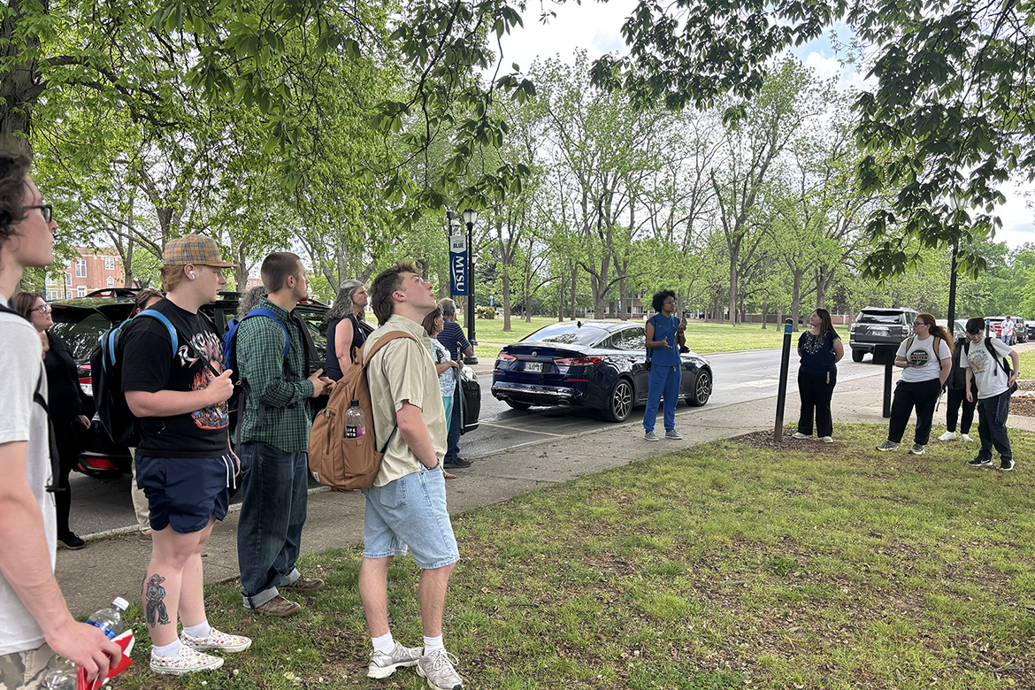 A crowd gathered Thursday, April 16, for the unveiling of the newly designated Level II Arboretum on the campus of Middle Tennessee State University in Murfreesboro, Tenn., stands underneath the tree canopy just outside the James Union Building as they listen to Department of Biology lecturer Danielle Brown talk about a few of the 73 specimens that are tagged and mapped across the 500-acre campus. (MTSU photo by James Cessna)