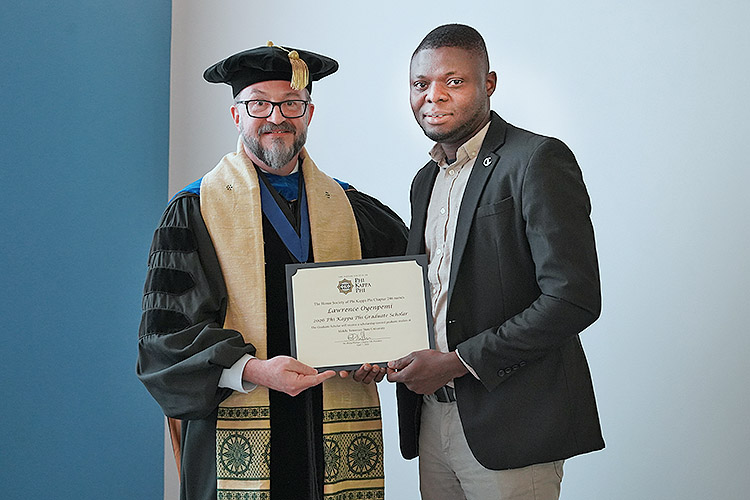Honors College Associate Dean Philip Phillips, left, president of the Phi Kappa Phi Honor Society Chapter 246 at Middle Tennessee State University in Murfreesboro, Tenn., left, presents a certificate to MTSU doctoral student Lawrence Oyenpemi, winner of the chapter’s Graduate Scholar Award for 2026. This competitive honor recognizes academic excellence among graduate students who are active members of the nation’s oldest all disciplinary honor society. (MTSU photo by Robin E. Lee)