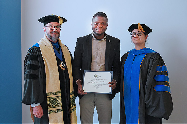 Honors College Associate Dean Philip Phillips, left, president of the Phi Kappa Phi Honor Society Chapter 246 at Middle Tennessee State University in Murfreesboro, Tenn., and Racha El Kadiri, associate dean of the MTSU College of Graduate Studies, right, present doctoral student Lawrence Oyenpemi with the chapter’s 2026 Graduate Scholar Award. This competitive honor recognizes academic excellence among graduate students who are active members of the nation’s oldest all disciplinary honor society. (MTSU photo by Robin E. Lee)