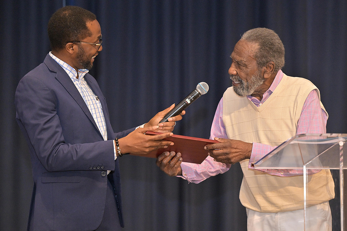 Middle Tennessee State University associate professor of soil science Samuel Haruna, left, associate dean for academic programs in the College of Basic and Applied Sciences, accepts the 2026 John Pleas Faculty Award from MTSU Department of Psychology Professor Emeritus John Pleas at a ceremony held Tuesday, March 31, in the James Union Building on campus in Murfreesboro, Tenn. (MTSU photo by James Cessna)
