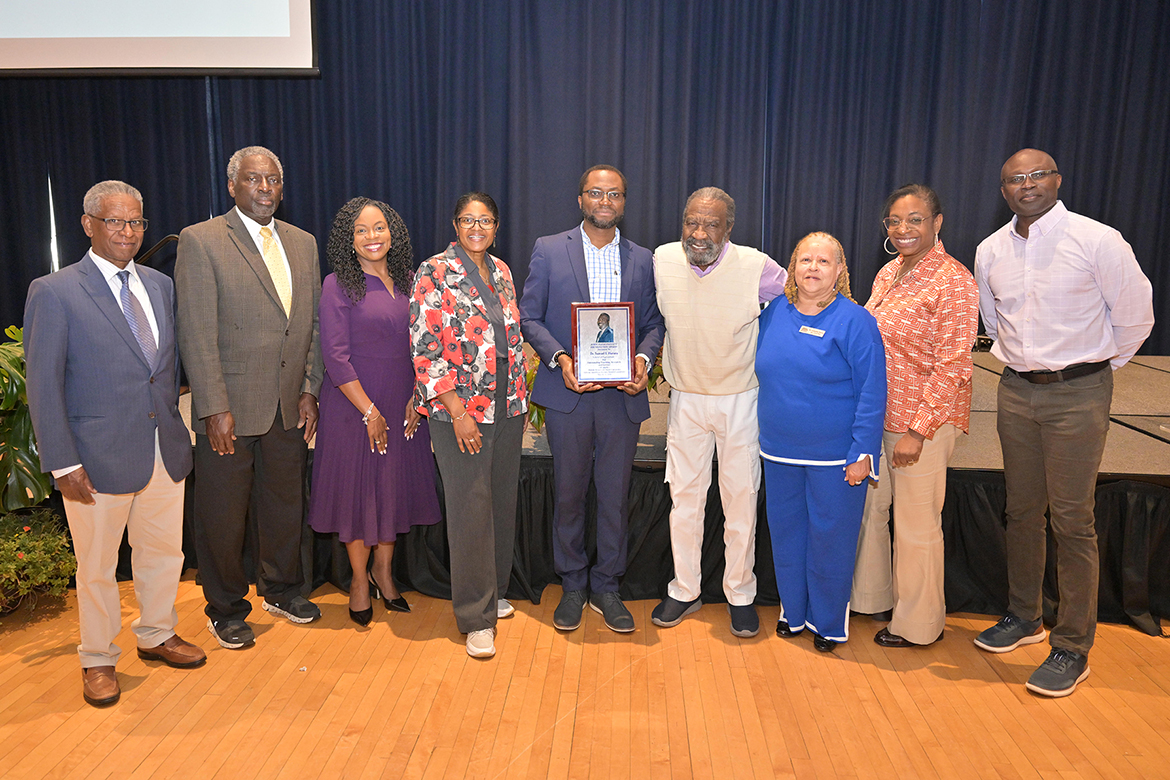 Middle Tennessee State University associate professor of soil science Samuel Haruna, center, holds the 2026 John Pleas Faculty Award he accepted during a ceremony held Tuesday, March 31, in the James Union Building on campus in Murfreesboro, Tenn. Pictured are, from left, previous Pleas award recipients Bichaka Fayissa, Alphonse Carter, Chandra Story, Leah Tolbert Lyons, Haruna, Professor Emeritus and award namesake John Pleas, Carmelita Dotson, Jennifer Woodard and Andrew Owusu. (MTSU photo by James Cessna)