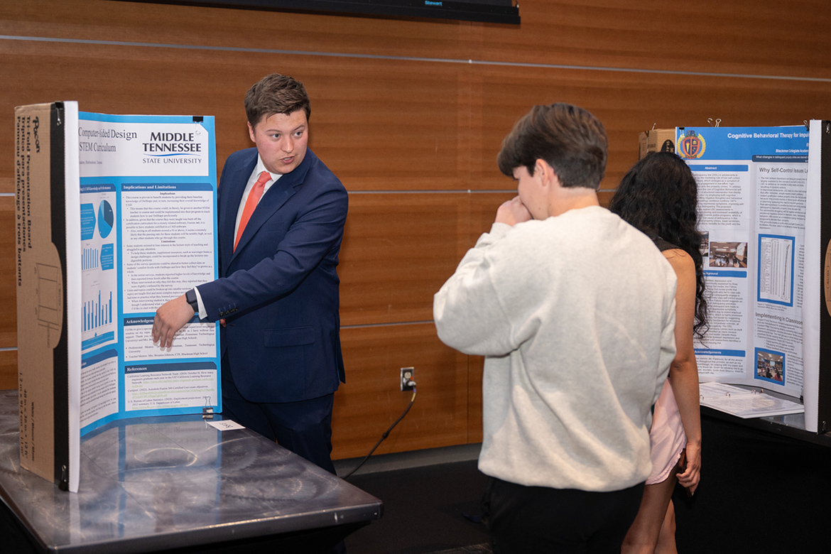 Blackman High School Collegiate Academy student Aiden Haynes, left, explains his research poster presentation during the Scholars Week 2026 Universitywide Poster Presentation held Friday, March 20, in the Student Union Building on campus in Murfreesboro, Tenn. (MTSU photo by James Cessna)