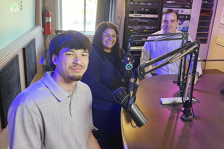 Three people in radio station studio behind microphones.