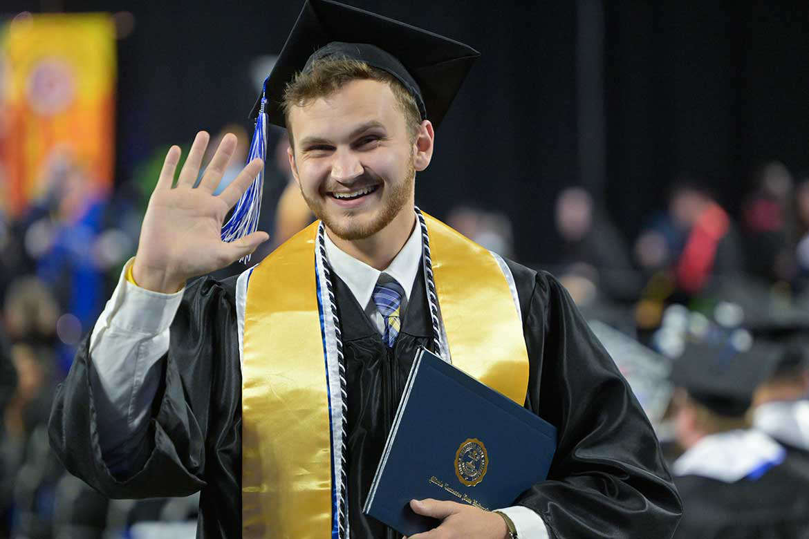 A Middle Tennessee State University spring 2026 graduate shows excitement as he holds his newly obtained degree and waves during the afternoon commencement ceremony.