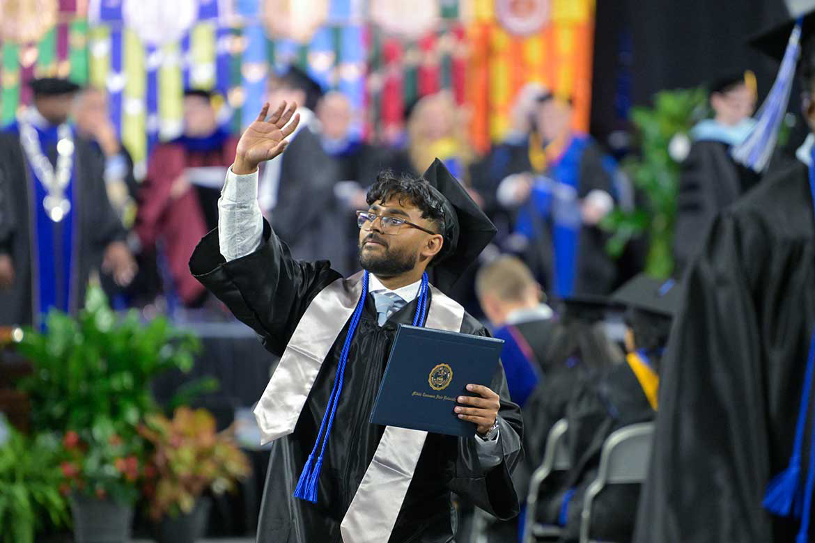 A Middle Tennessee State University spring 2026 graduate holds his newly obtained degree and waves during the afternoon commencement ceremony held in early May in Murphy Center.