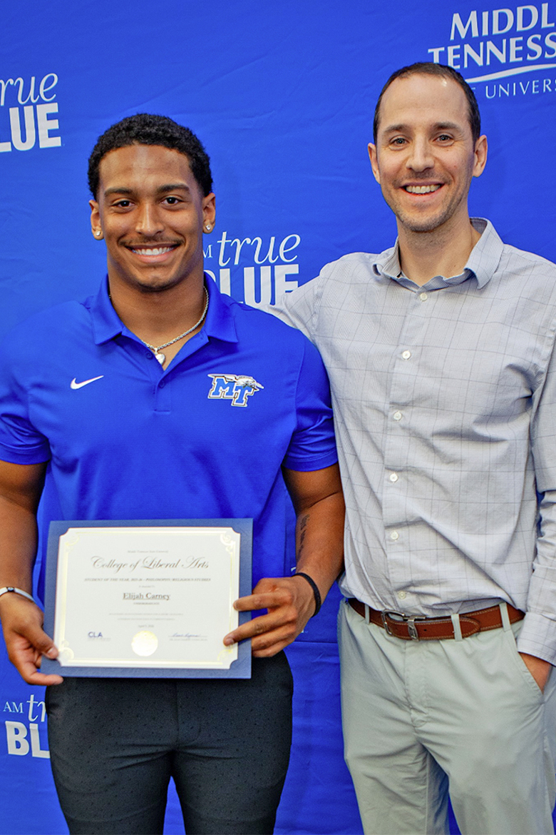 Elijah Carney, a senior philosophy and religious studies major at Middle Tennessee State University in Murfreesboro, Tenn., left, poses for a photo next to assistant professor of philosophy Gregory Slack, while holding his Outstanding Student of the Year award at the annual College of Liberal Arts awards ceremony held Thursday, April 9, 2026. Carney also plays linebacker for the MTSU Blue Raiders football team. (MTSU photo by J. Intintoli.)