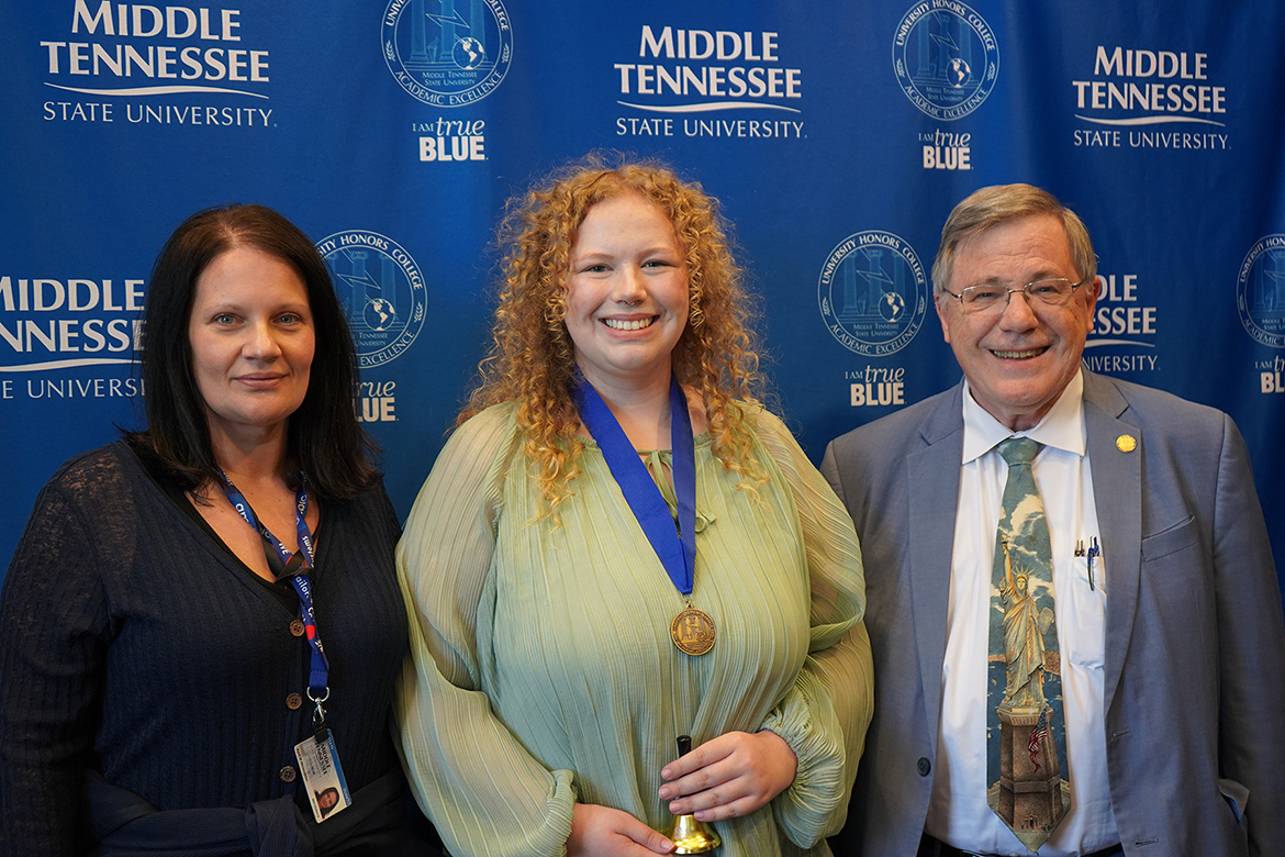 Alexis Katz, center, a biology major, is shown with faculty mentor April Weissmiller, left, associate professor of biology, and John Vile, dean of the MTSU Honors College, in front of MTSU blue backdrop.