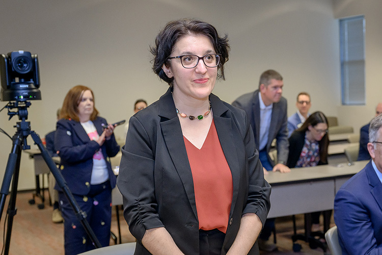 Hanna Terletska standing in meeting room with other people, video camera in background.