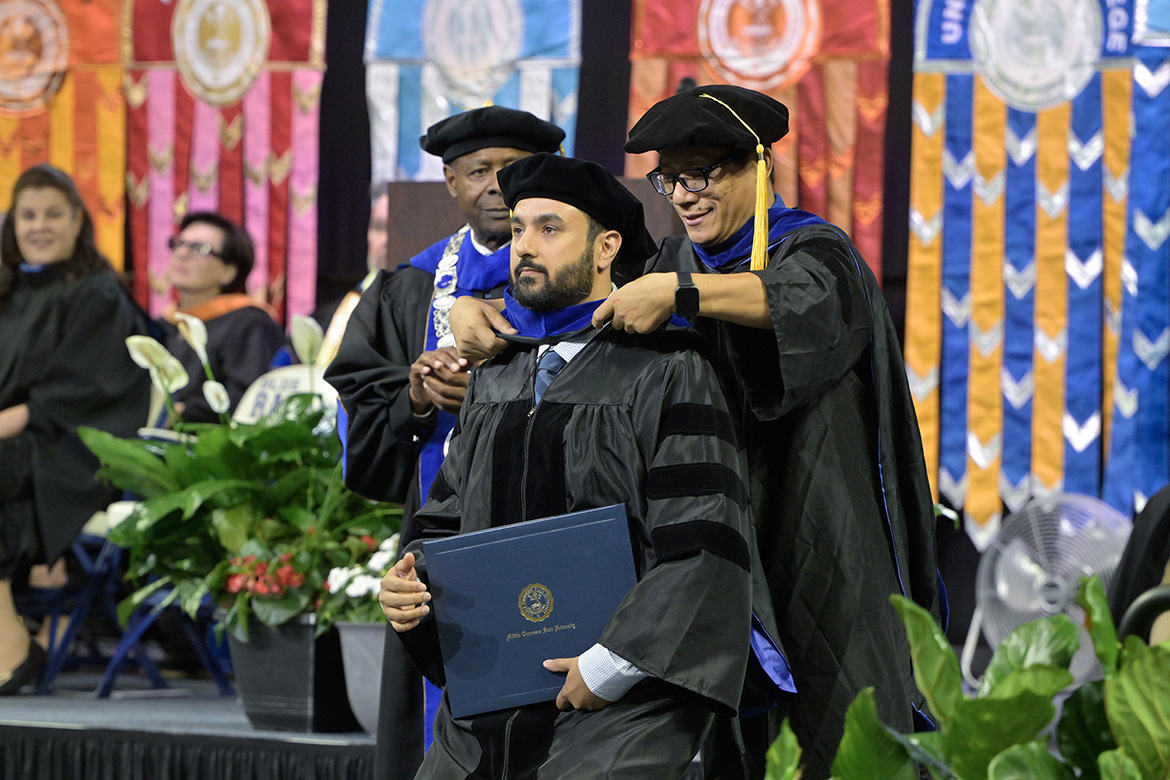 Middle Tennessee State University graduate Yousaf Abdul Khaliq is hooded by his professor, Forrest Wang, during the first of three spring commencement ceremonies on Friday, May 8, at Murphy Center.