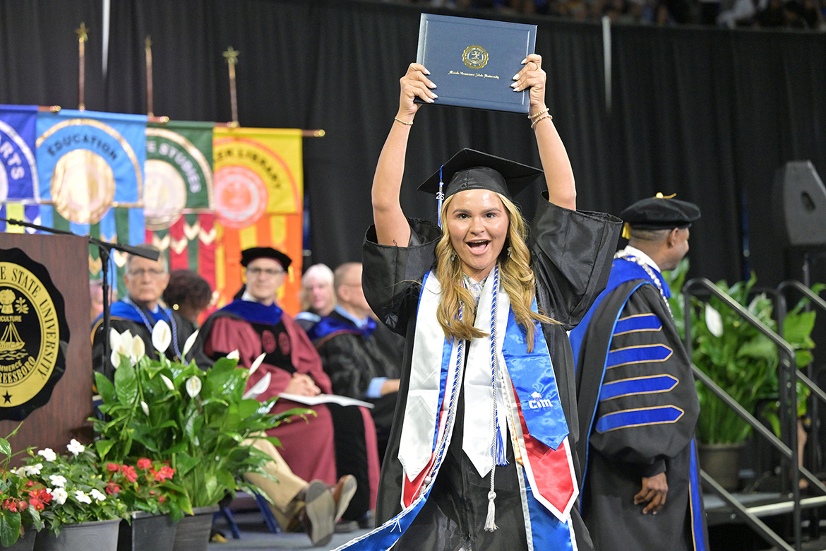A proud Class of 2026 graduate holds up her diploma cover after crossing the stage during the Friday, May 8, spring commencement ceremony inside Murphy Center at Middle Tennessee State University.