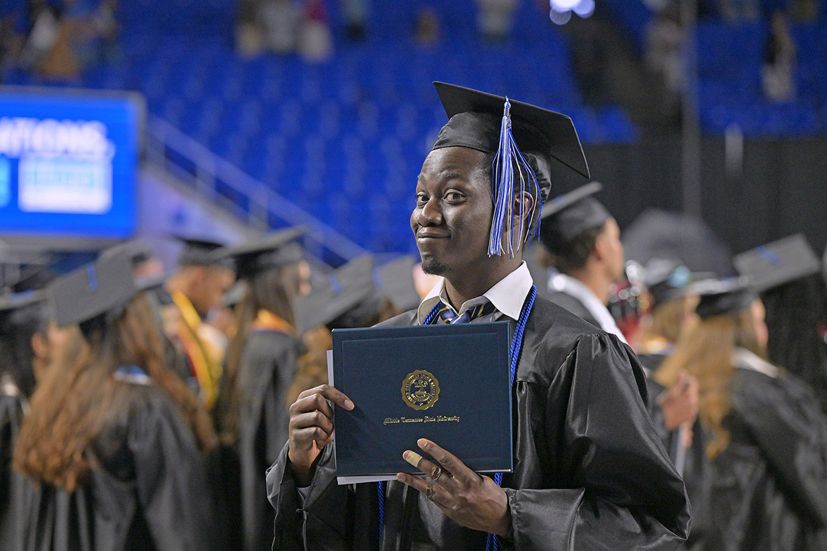 A proud Class of 2026 graduate gives a grin as he holds up his diploma cover on Saturday, May 9, during the morning commencement ceremony held inside Murphy Center at Middle Tennessee State University in Murfreesboro, Tenn. (MTSU photo by James Cessna)
