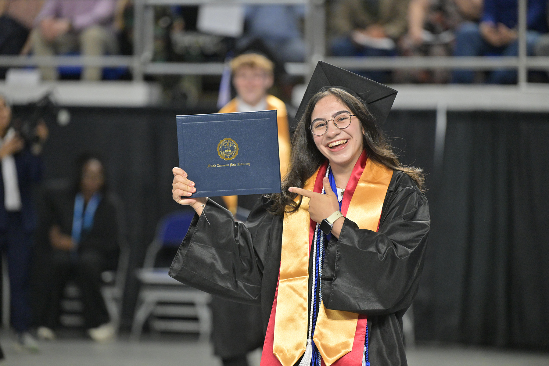Spring Class of 2026 graduate Gamze Mert holds up her diploma cover after crossing the stage during the Saturday, May 9, spring commencement ceremony inside Murphy Center.