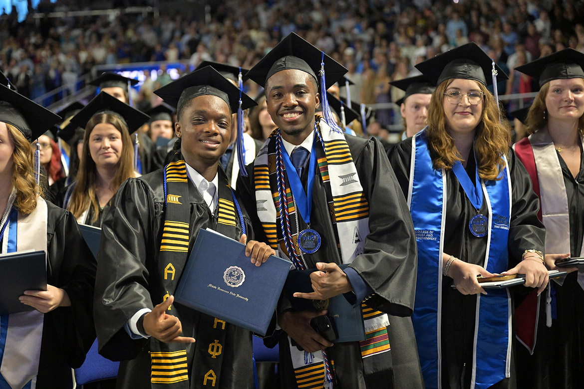 Class of 2026 graduates smile for the camera, including two Alpha Phi Alpha Fraternity brothers, center, during the afternoon commencement ceremony held Saturday, May 9, inside Murphy Center at Middle Tennessee State University in Murfreesboro, Tenn. (MTSU photo by James Cessna)