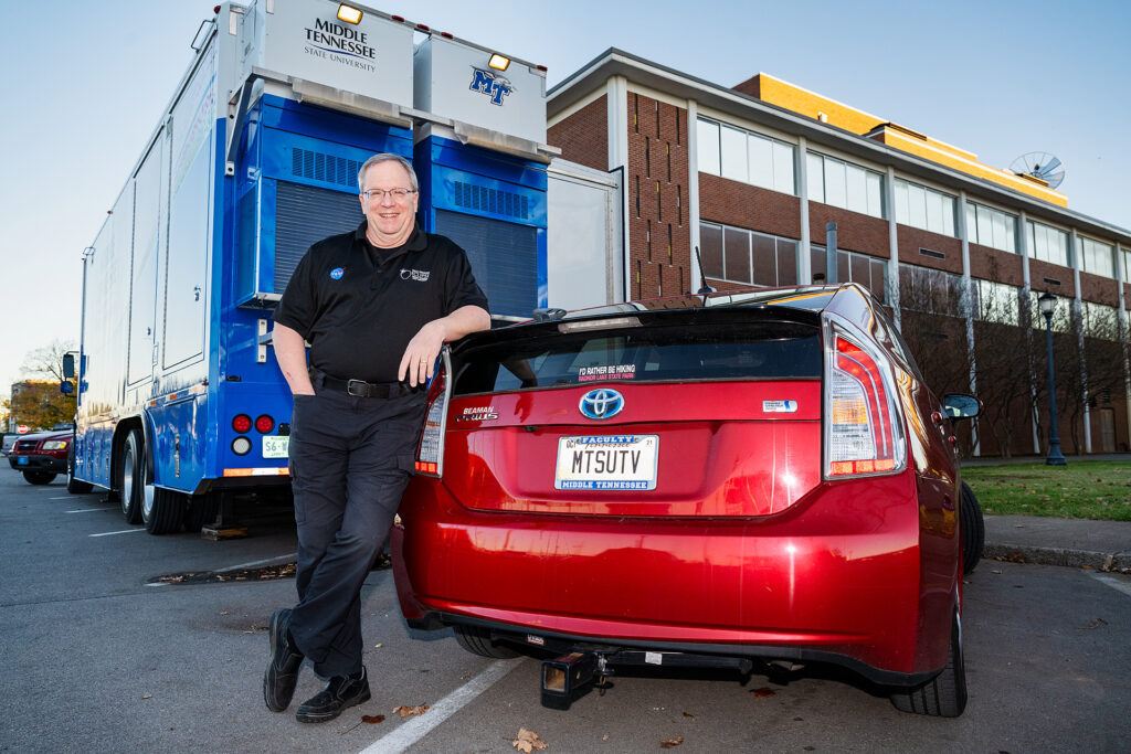 MTSU Department of Media Arts professor Robert "Bob" Gordon Jr. displays his car's customized license plate, "MTSUTV," outside the Boutwell Dramatic Arts Auditorium as his students work inside Tucker Theatre to record the MTSU Dance Theatre's 2020 Fall Dance Concert for broadcast Saturday, Nov. 21. Behind him is the College of Media and Entertainment's $1.7 million Mobile Production Lab, aka "The Truck." (MTSU photo by Andy Heidt)