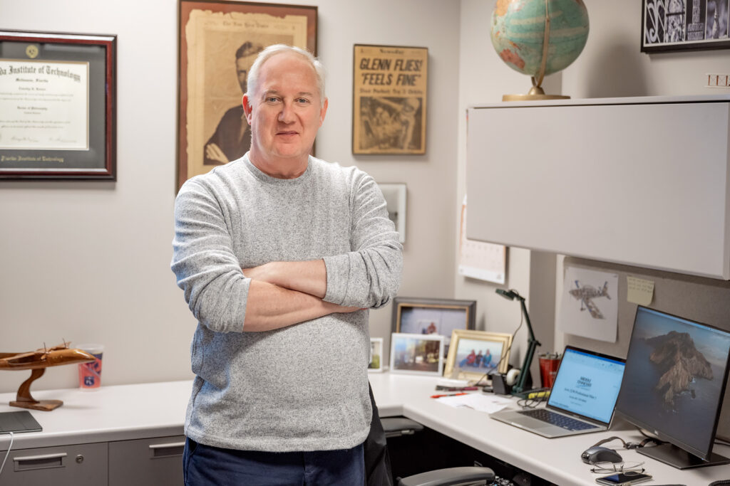 Tim Rosser poses for portraits in his office and discusses exam materials with students.