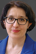 Hanna Terletska, a woman with light skin, brown hair and black-framed glasses, looks at the camera.
