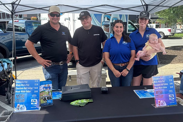 Middle Tennessee State University Dairy Farm team members staff the MTSU Creamery booth on June 6, 2026, at the Main Street Murfreesboro Saturday Market, which is held downtown from 8 a.m. to noon each Saturday from May through the end of October. Pictured are, from left, James Flatt, Farm Lab director; MTSU students Evan Osborne of Murfreesboro, Tenn., and Calle Shwani from Nashville, Tenn.; and farm lab assistant Erin Frantz, holding daughter, Emery. (Submitted photo)