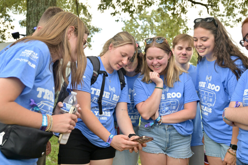 Group of MTSU journalism students huddled looking at cellphone.