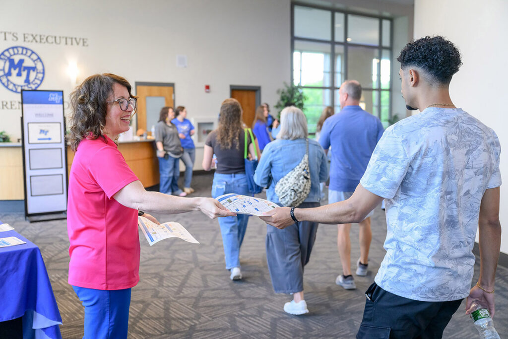 Rachel Hunter, marketing manager for Aramark Collegiate Hospitality Services at Middle Tennessee State University in Murfreesboro, Tenn., hands out dining maps in the Student Union Ballroom hallway on May 27 during New to Blue Orientation, when hundreds of incoming first-year and transfer students learn all about campus. (MTSU photo by J. Intintoli)