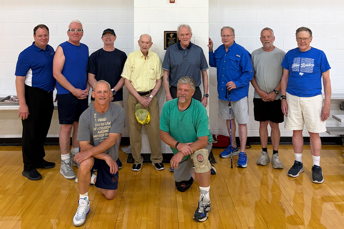 Omri Rawlins, back row, fourth from left, stands with fellow members of the “Noon Basketball Association” gathered around a plaque dedicated in his honor inside the Middle Tennessee State University Campus Recreation Center in Murfreesboro, Tenn. The Rec recently dedicated a basketball court to Rawlins, a retired longtime faculty member who served as the group's longtime 