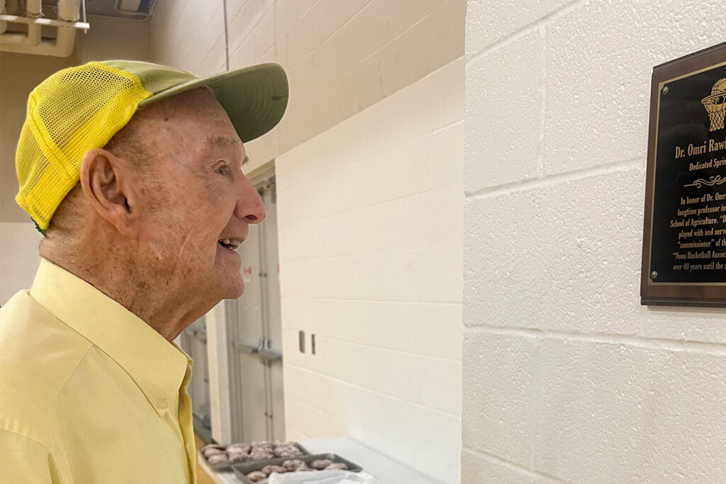 Retired Middle Tennessee State University School of Agriculture professor Omri Rawlins reads the plaque commemorating the dedication of "Dr. Omri Rawlins Court" inside the Campus Recreation Center in Murfreesboro, Tenn. Rawlins participated in the facility's weekly “Noon Basketball Association” games for more than four decades. (Submitted Photo)