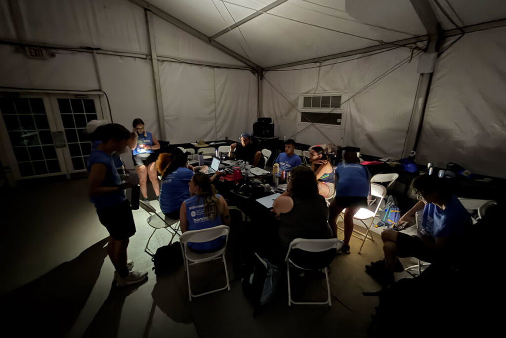 Students from Middle Tennessee State University’s student-run media outlet Sidelines work in the media tent at the Bonnaroo Music and Arts Festival held June 11-14, 2026, in Manchester, Tenn., by flashlights after the music festival experienced a power outage on June 12. (MTSU photo by Andrew Oppmann)