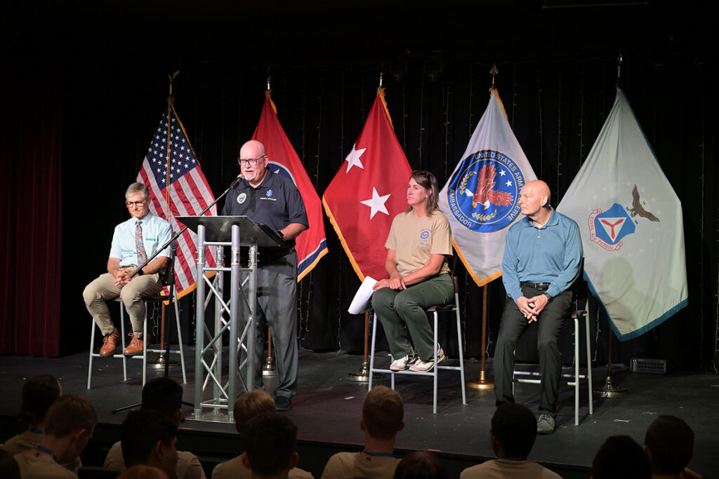Andrew Oppmann, at podium, Middle Tennessee State University’s vice president for marketing and communications and a Civil Air Patrol lieutenant colonel, welcomes CAP cadets in the U.S. Air Force Auxiliary’s National Cadet Engineering Technology Academy held July 18-25, 2026, on campus in Murfreesboro, Tenn. Seated on stage, from left, are Greg Van Patten, dean of the College of Basic and Applied Sciences; Beth Loughry, public relations specialist in Marketing and Communications; and retired Lt. Gen. Keith Huber, senior adviser for veterans and leadership initiatives at MTSU. (MTSU Photo by James Cessna)
