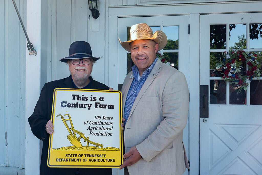 Tennessee Department of Agriculture Commissioner Andy Holt, right, and state historian Carroll Van West, who retired June 30, 2026, as director of the Center for Historic Preservation at Middle Tennessee State University in Murfreesboro, Tenn., hold one of the distinctive yellow Tennessee Century Farms markers, which recognize farms that have remained in continuous family ownership and agricultural production for at least 100 consecutive years. (Submitted photo)