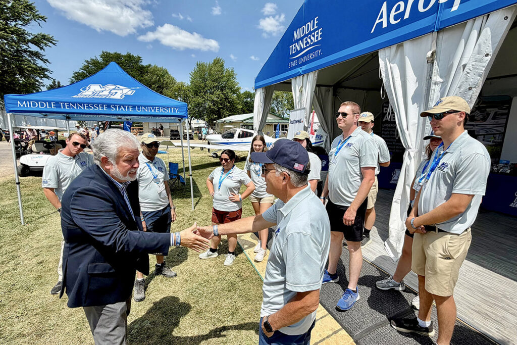 Rick Leach, president and CEO of GoJet Airlines, left, shakes hands with Middle Tennessee State University Provost Mark Byrnes during Leach’s visit to the MTSU Aerospace Department’s tent at the 2026 EAA AirVenture in Oshkosh, Wis. (MTSU Photo by Andrew Oppmann)
